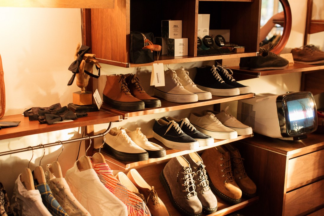 Wooden shelving displays various boots and shoes with price tags in Mohawk general store.