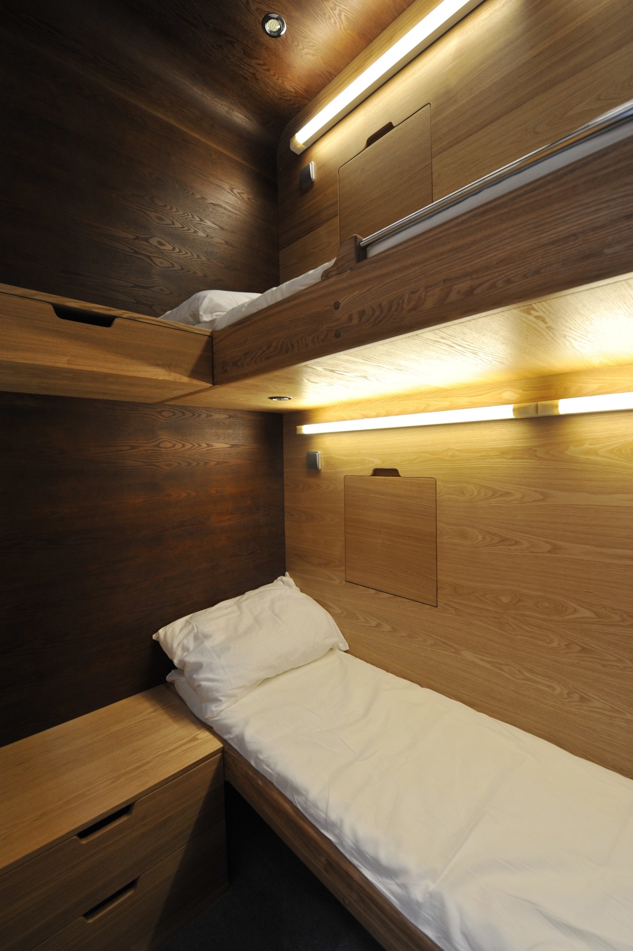 Interior of Sleepbox, a compact ash wood sleeping pod with a bed, pillow, and integrated lighting at Moscow airport.