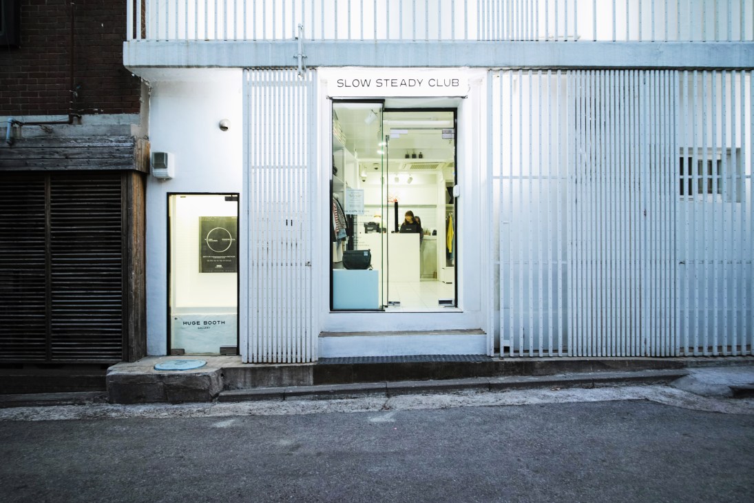 Slow Steady Club storefront with white corrugated metal facade and glass doors in Seoul.