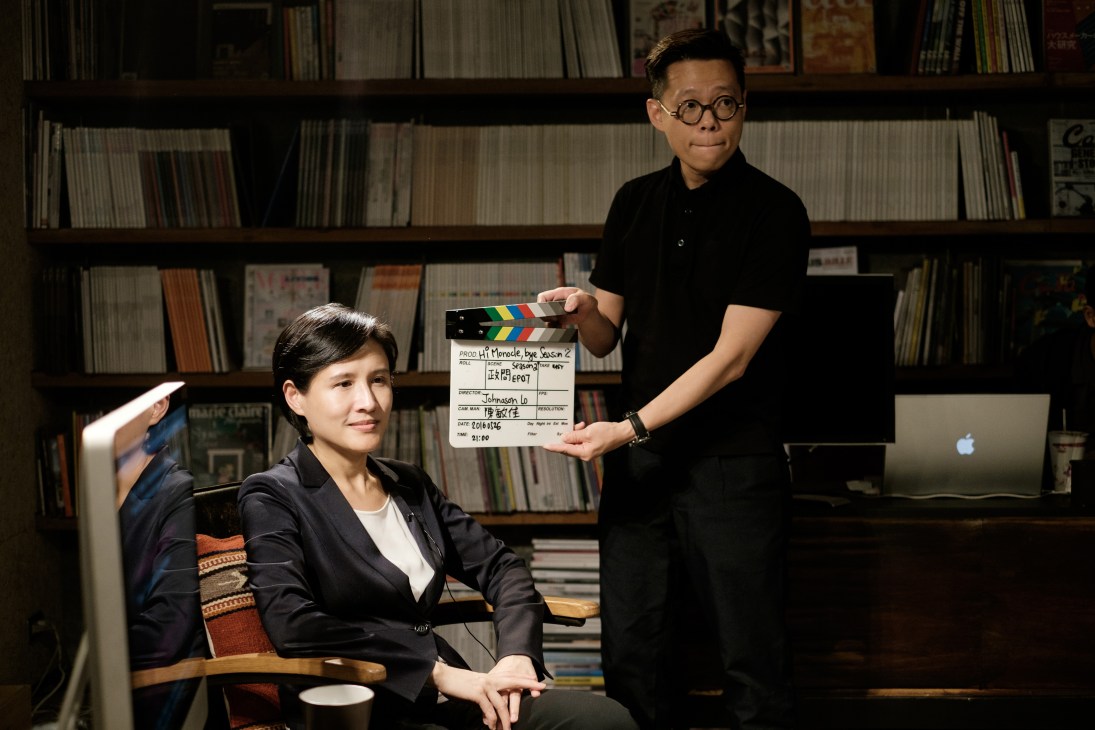 Art director Yu Feng holds a film clapperboard while preparing culture minister Cheng Li-chun for her interview in front of a bookshelf.