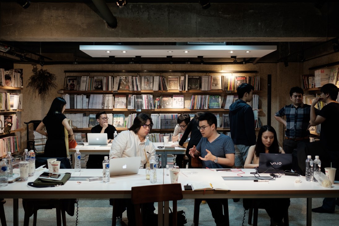 Team members gathered around a table in a magazine library discussing the Talk to Taiwan broadcast.