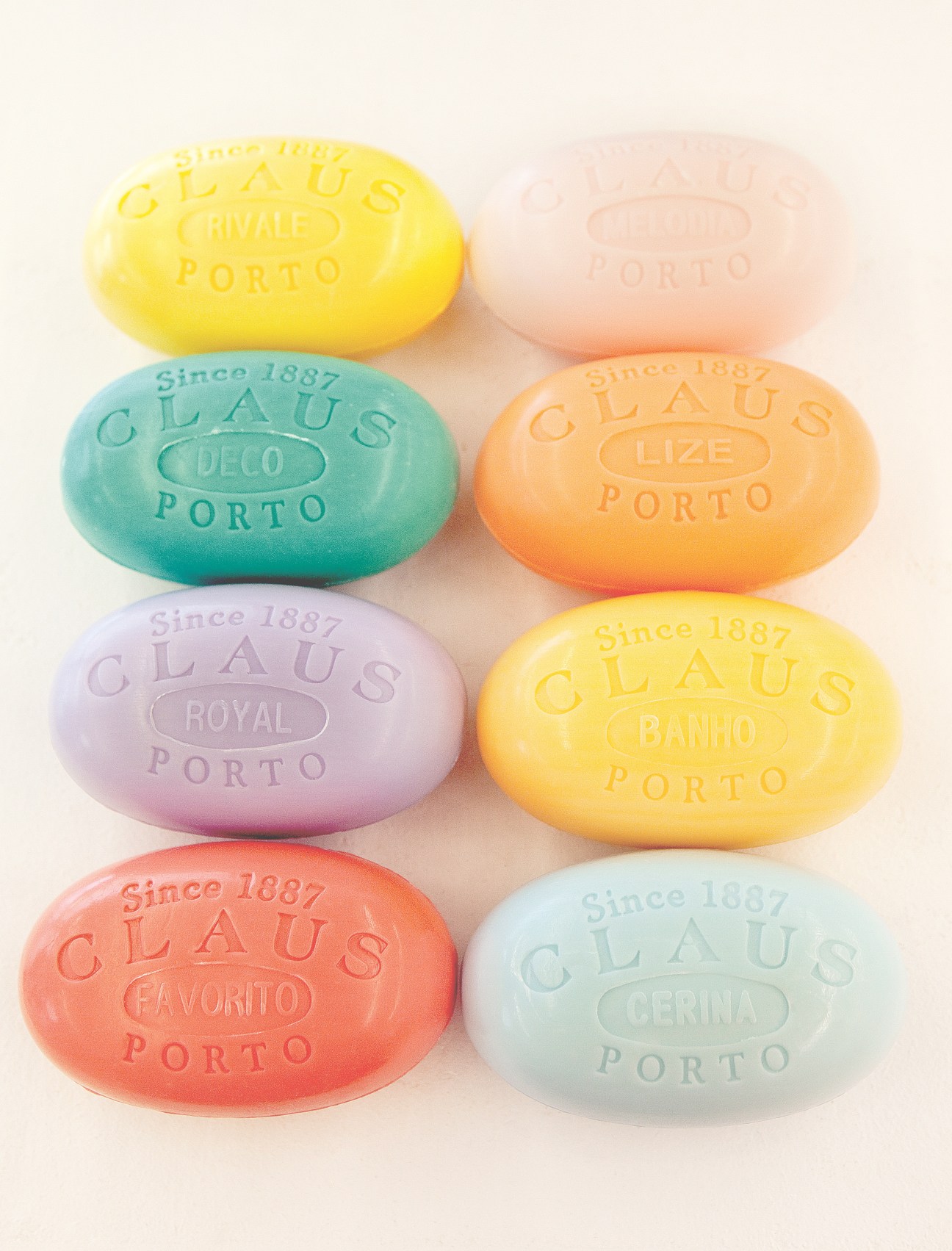 Eight colorful Claus Porto soap bars arranged in rows, each stamped with the brand name and scent variety.