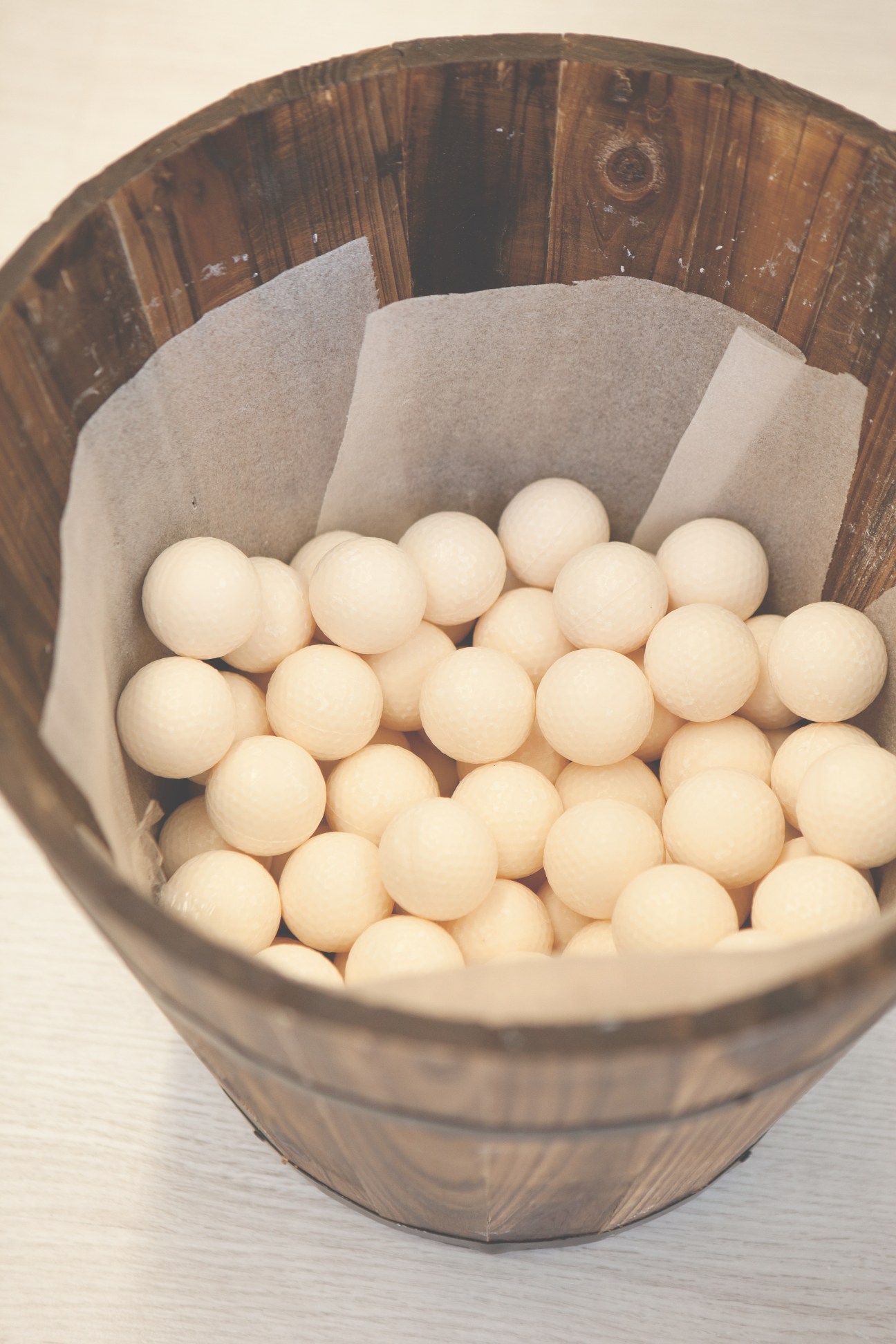 Cream-colored soap balls in a wooden barrel lined with parchment paper.