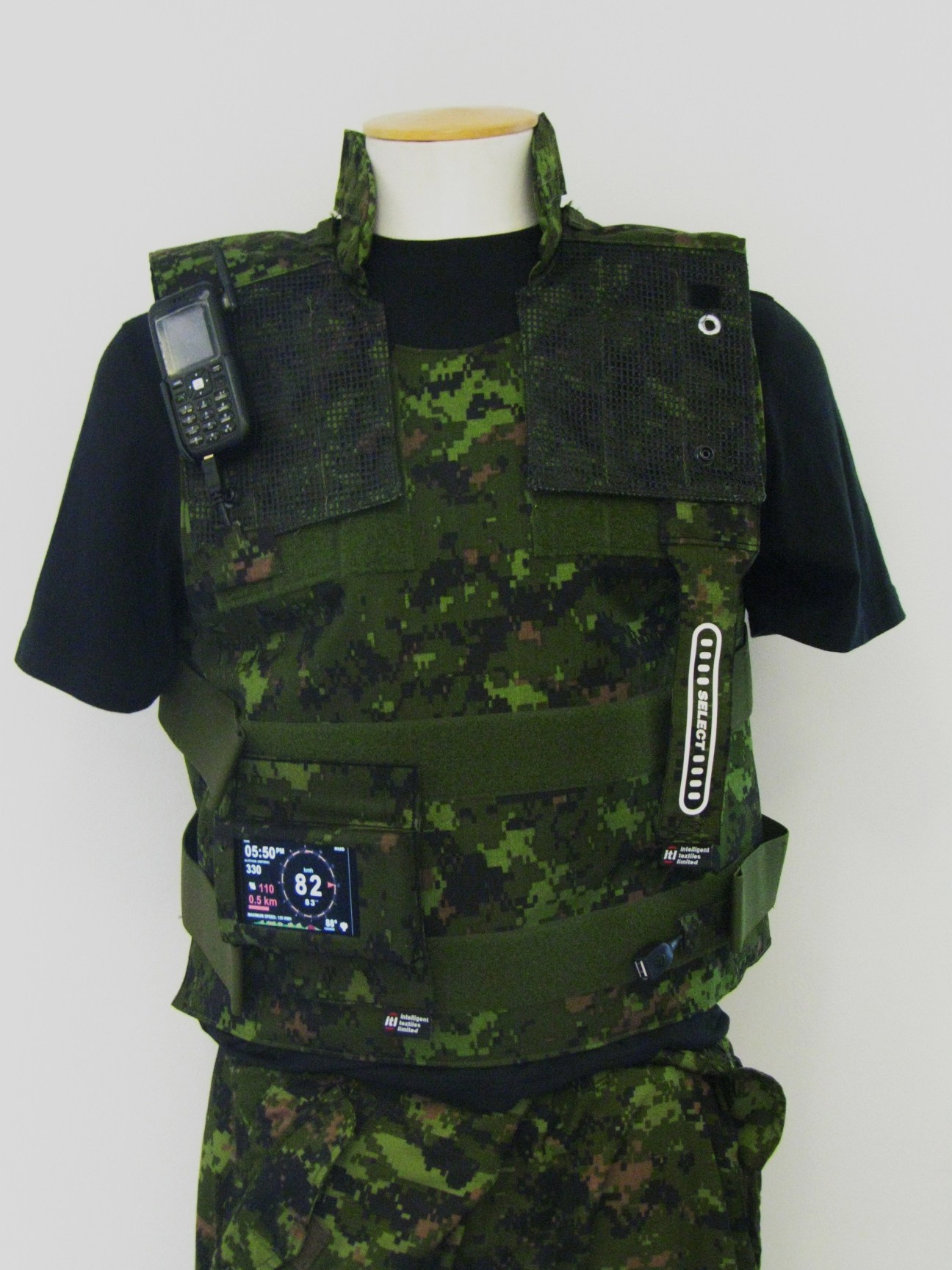 Military uniform with integrated smart fabric displays, sensors, and wireless technology attachments on a mannequin.