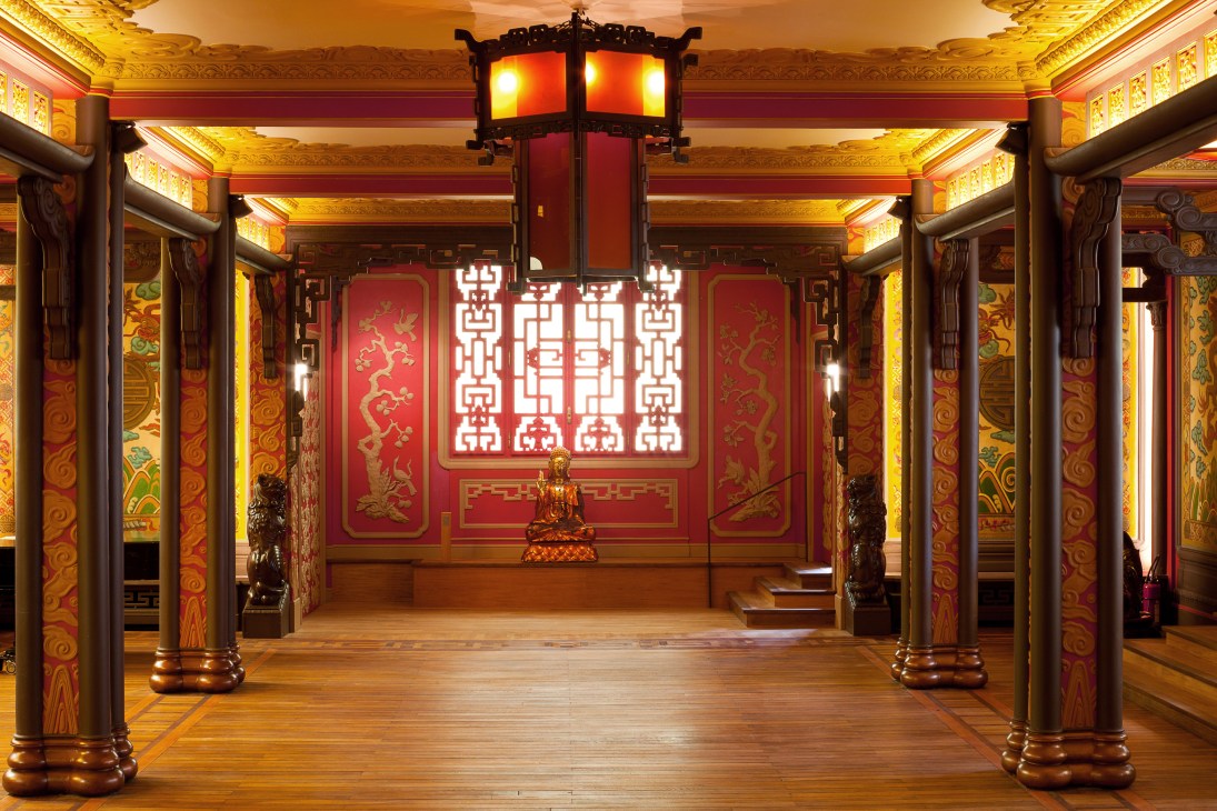 Interior of South-East Asia House with ornate red and gold decorative panels, wooden columns, and traditional Asian architectural details.