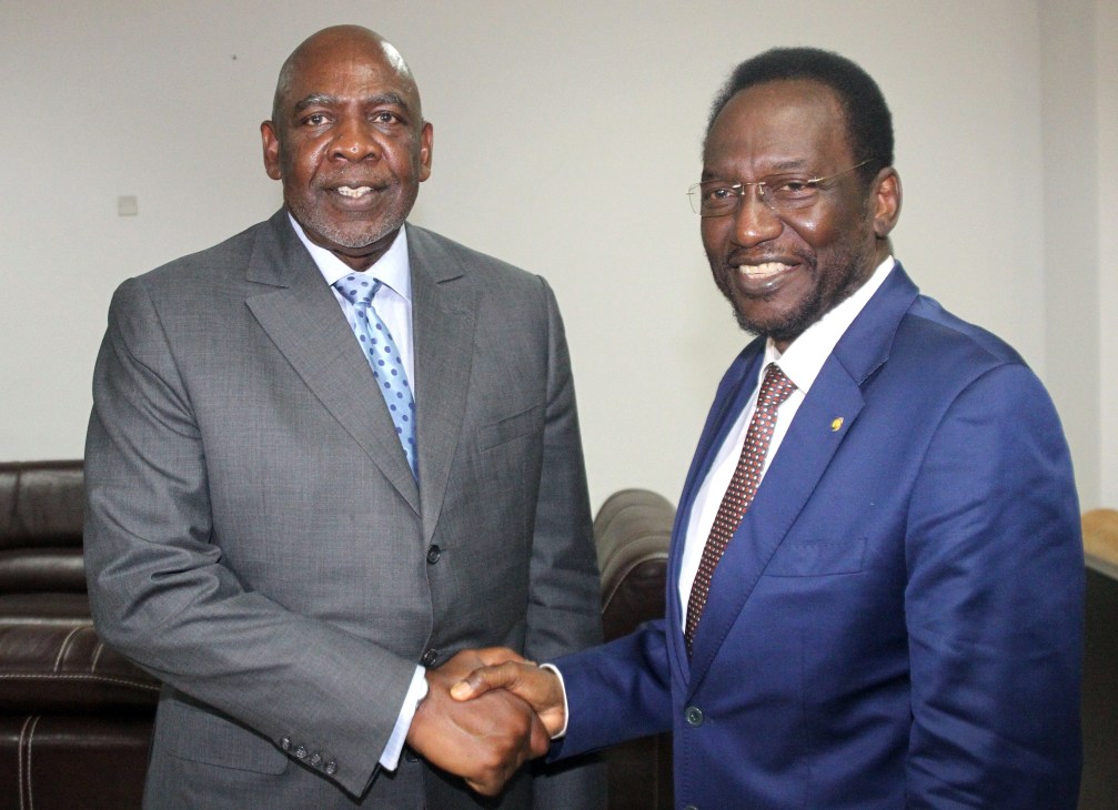 Two men in business suits shaking hands indoors.