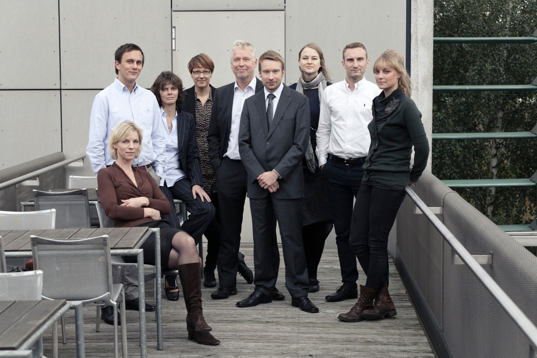 Nordic embassy staff pose on a modern terrace with glass panels and metal railings.