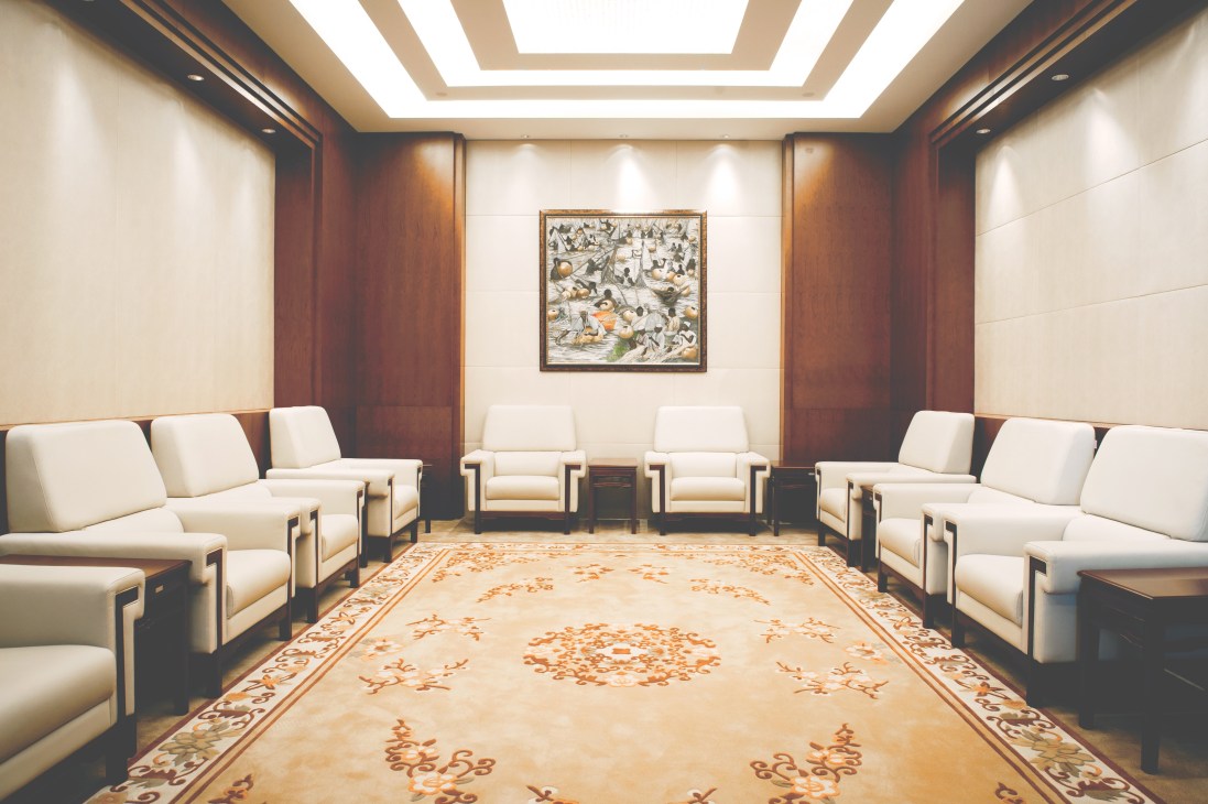 Luxurious VIP meeting room with cream armchairs, dark wood paneling, and framed wildlife artwork at the African Union Conference Center.