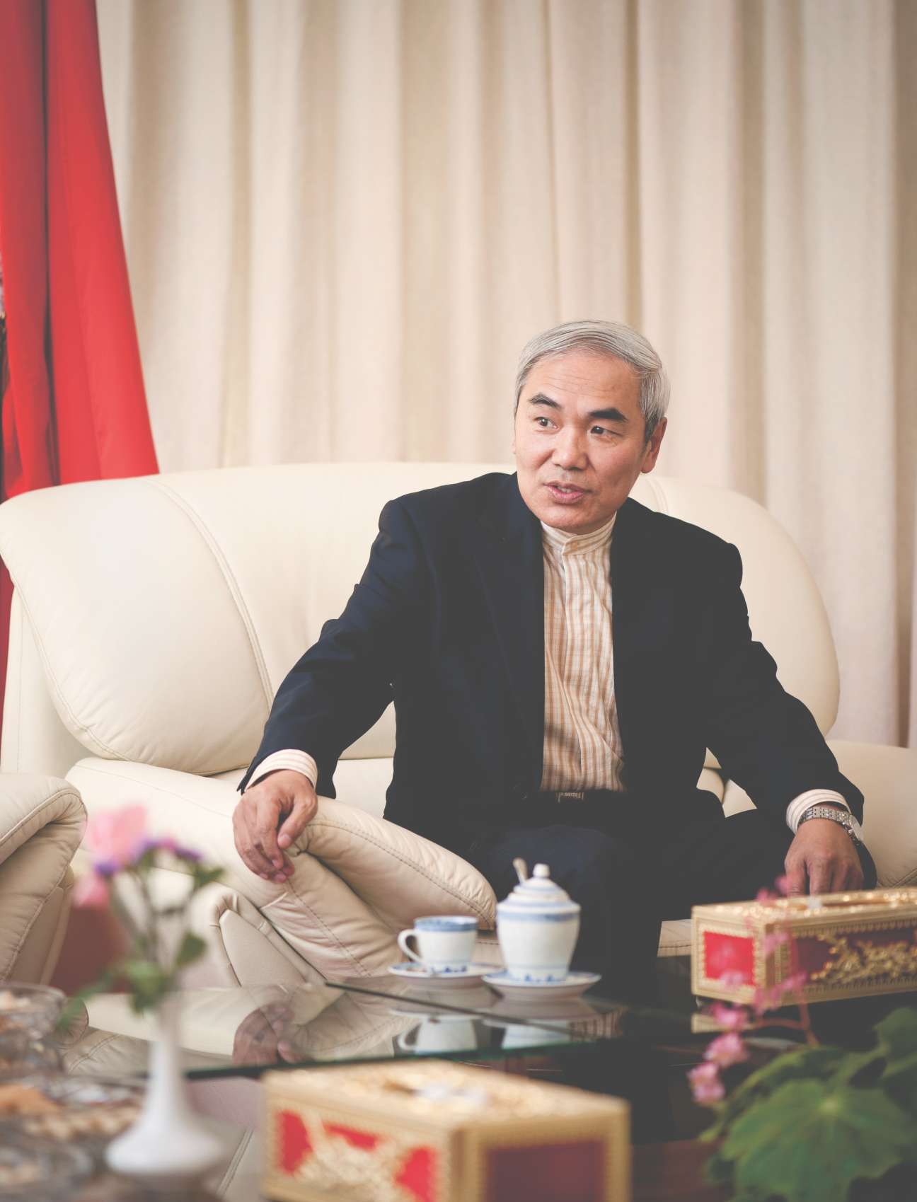 Chinese ambassador Xie Xiaoyan sits on a cream sofa in front of a red Chinese flag during an interview.