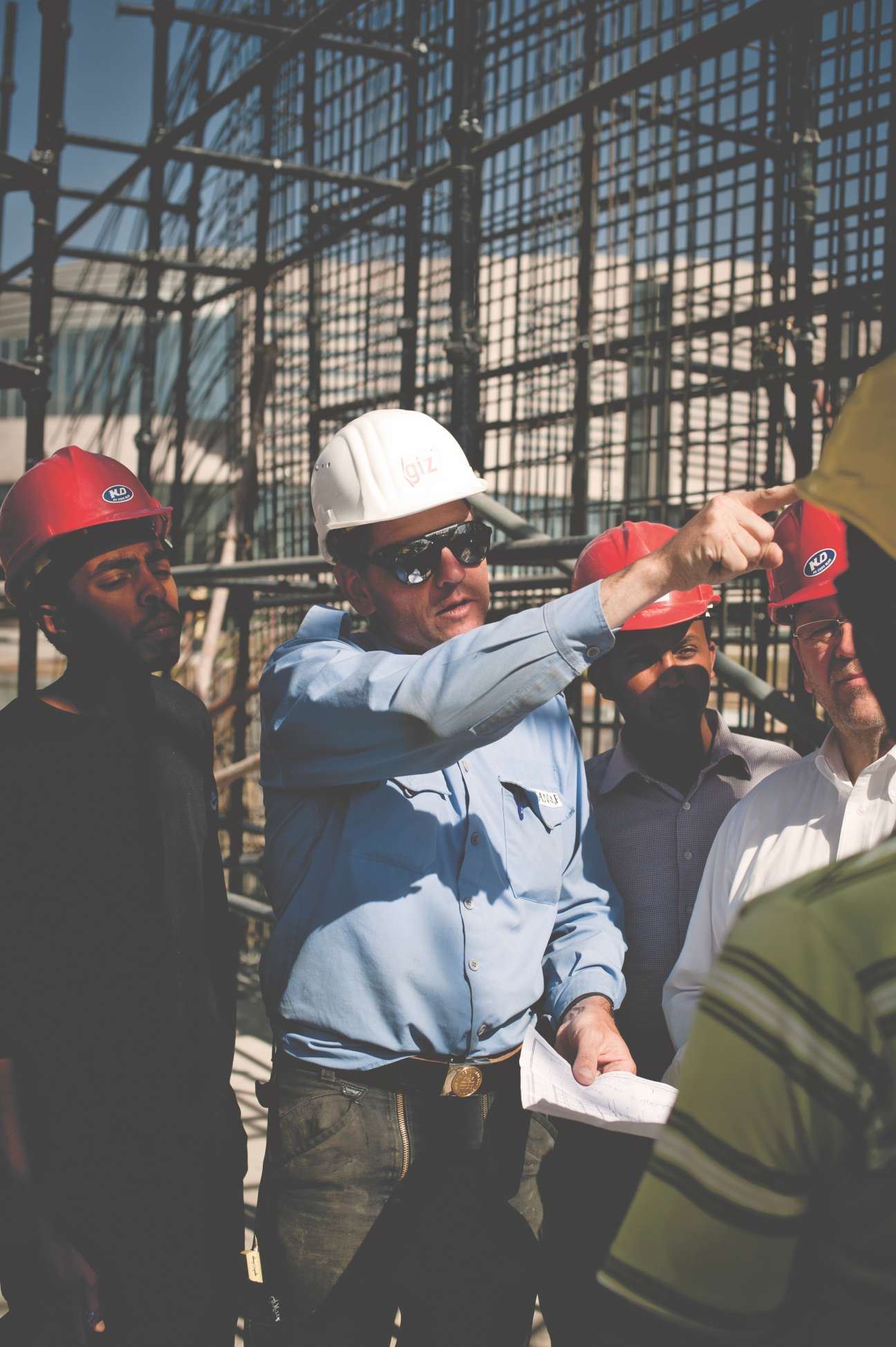 German and Ethiopian workers on construction site with scaffolding in background