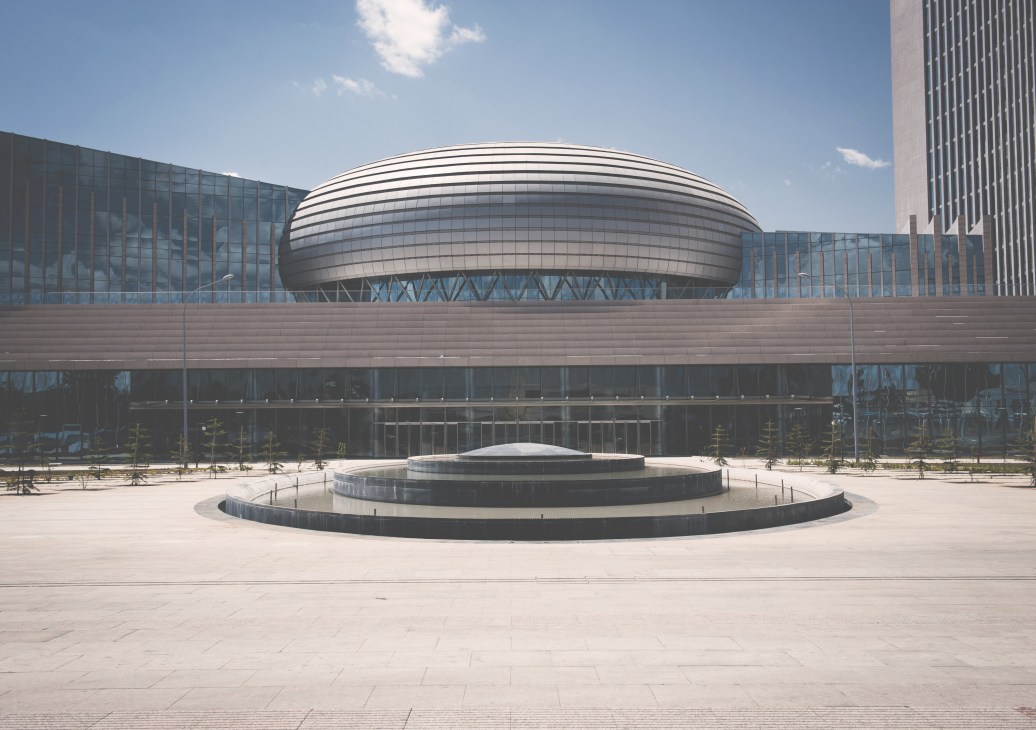 African Union Conference Center in Addis Ababa with distinctive domed roof, glass facades, and circular plaza with reflecting pool in foreground.