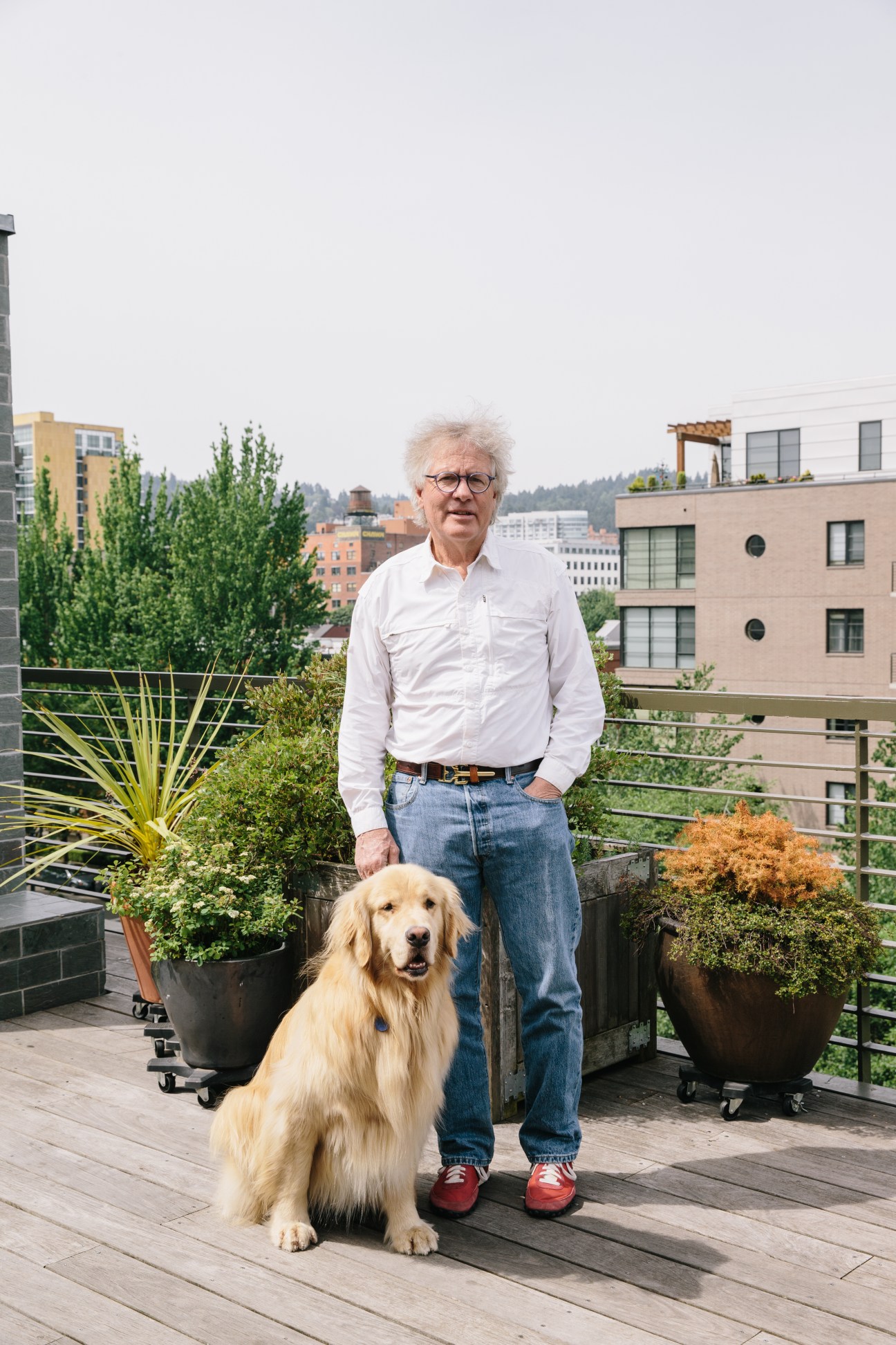 Spencer Beebe stands on a rooftop deck with his golden retriever Bobcat, overlooking Portland's Pearl District.