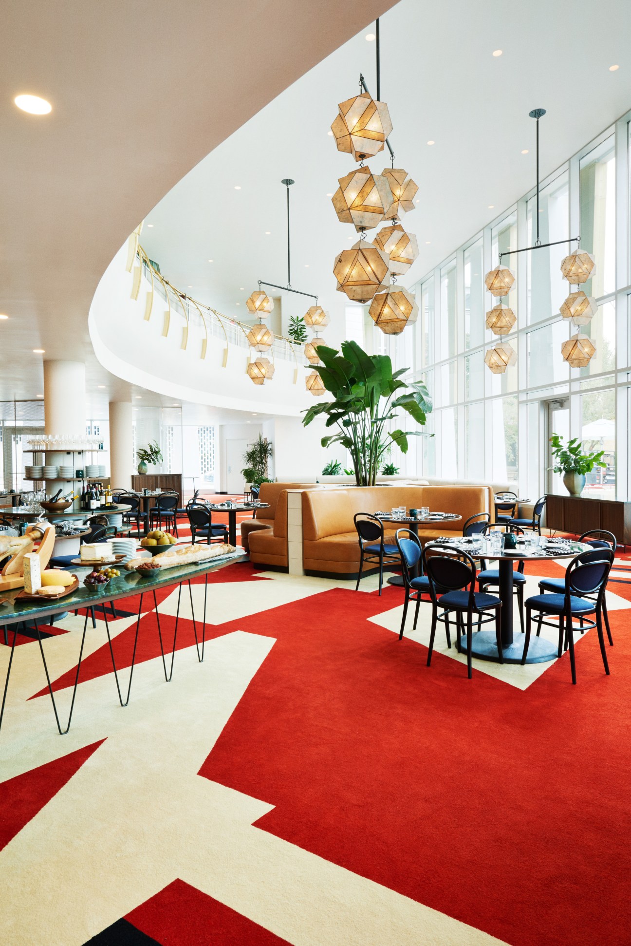 Modern lobby with geometric wooden pendant lights, red and white floor patterns, and leather seating at The Durham Hotel.