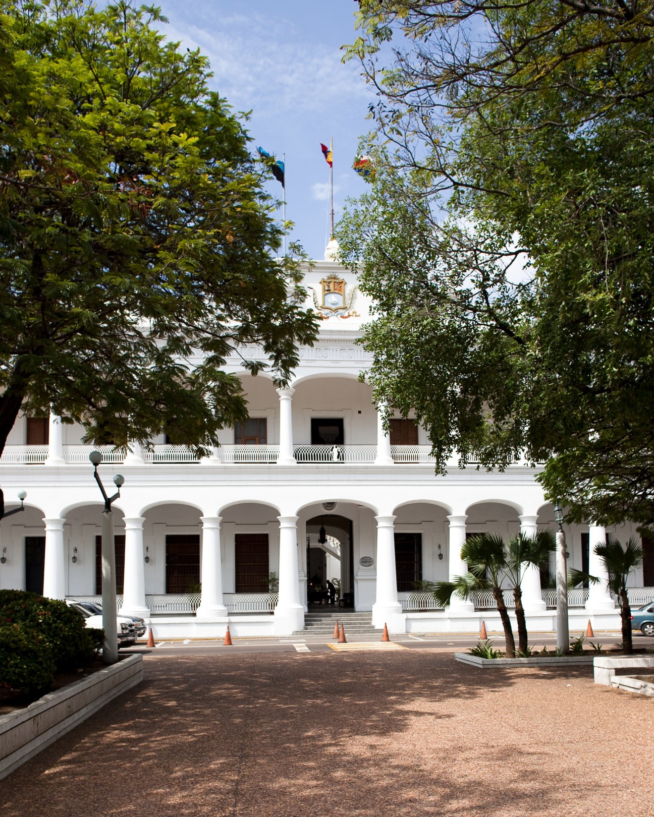 White colonial-era Palacio de Gobierno building with arched colonnade and Venezuelan flags flying from the roof.