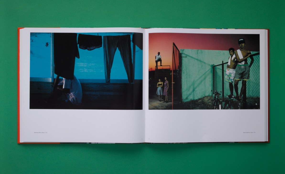 Open book with red spine displaying street photography by Alex Webb across two pages on green background.
