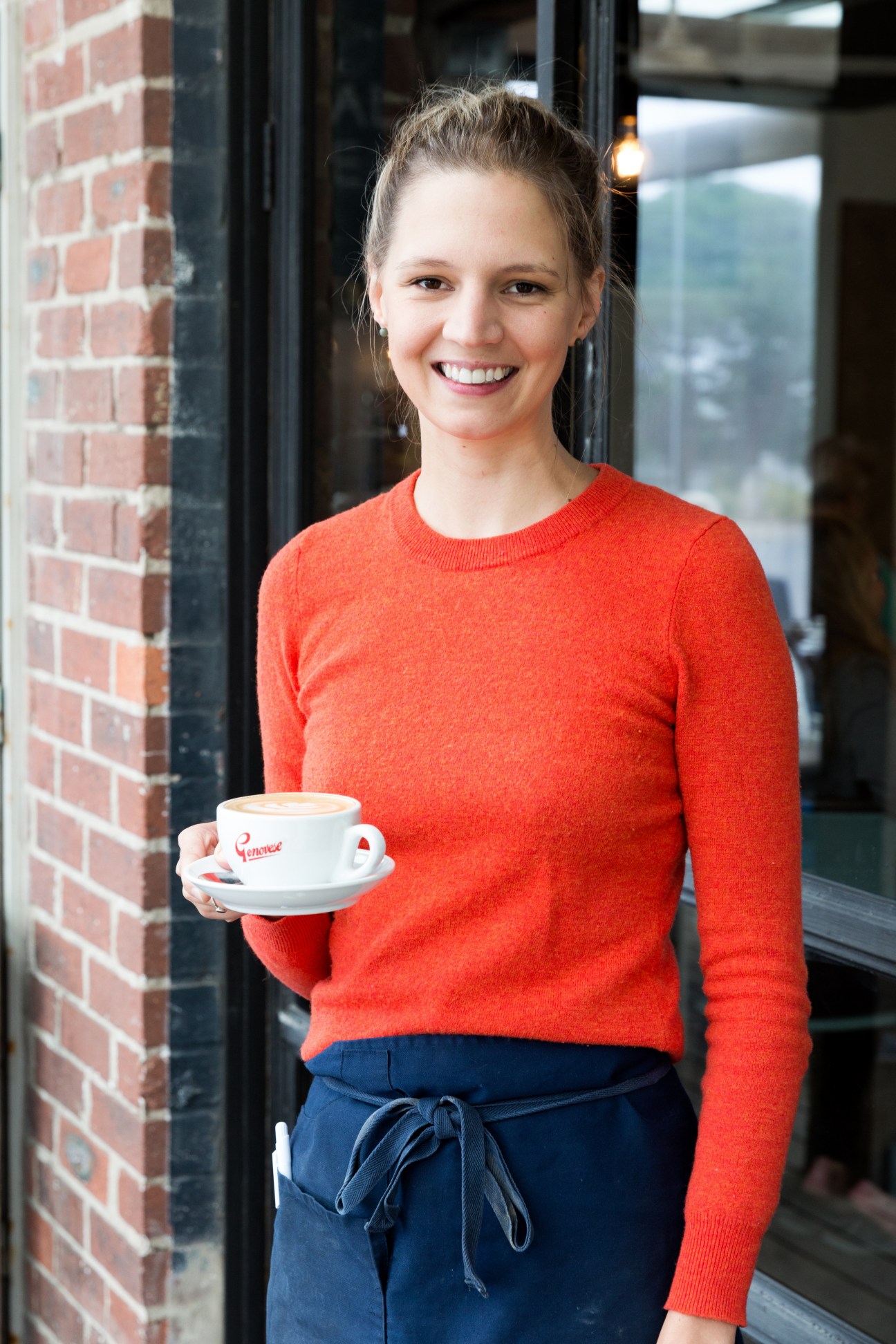 Stephanie Luxton, a Wye River General Store worker, holds a coffee cup while smiling at the camera outside the store.