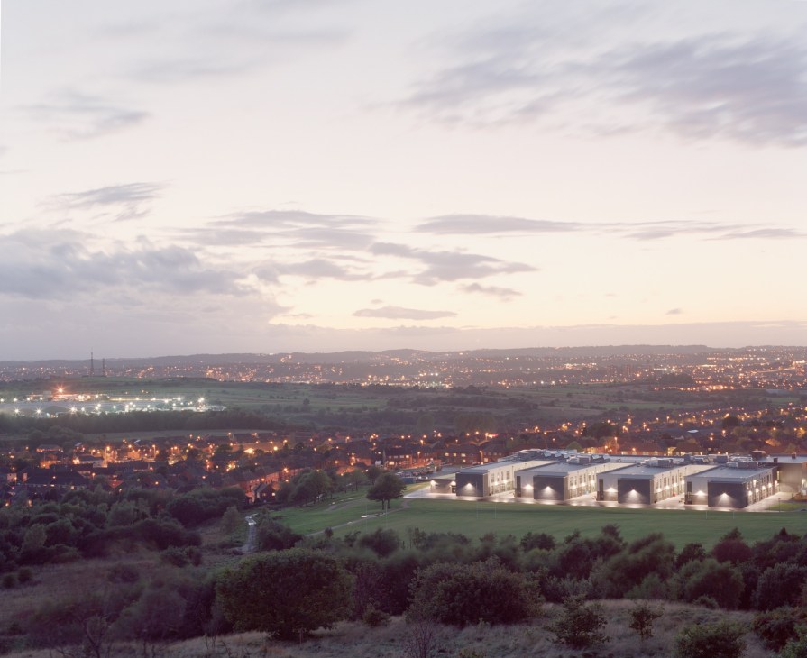 Aerial view of Stoke-on-Trent at dusk with illuminated buildings and residential areas sprawling across the landscape.