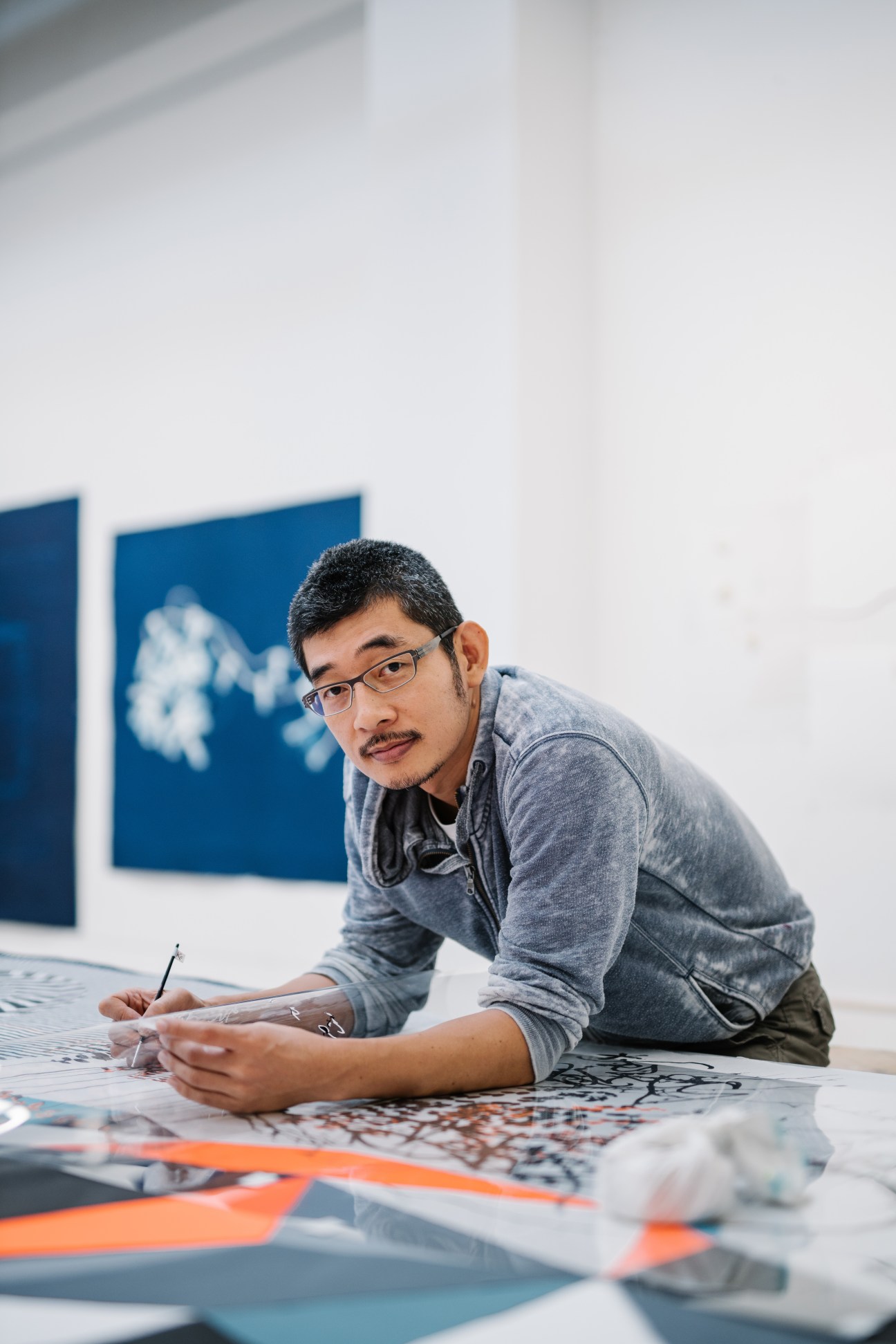 Chief printer and project leader Eitaro Ogawa works on a print design at a table in the STPI workshop.