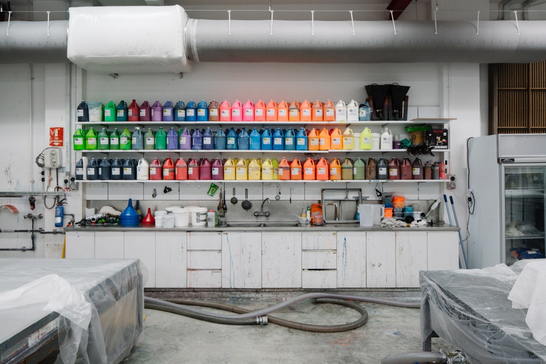 Shelves of colorful ink bottles and printing supplies in STPI workshop.