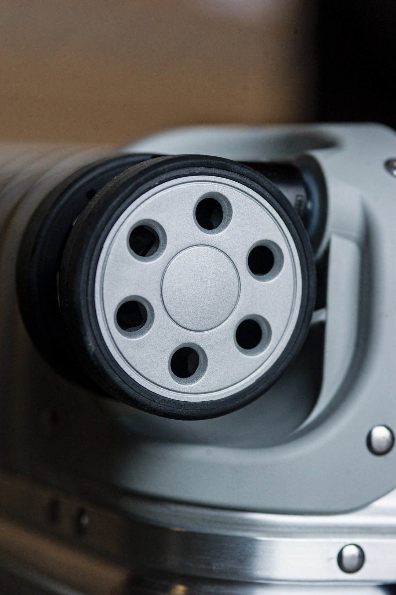 Close-up of Rimowa suitcase's patented Multiwheel system with metal hub and black rubber tire.