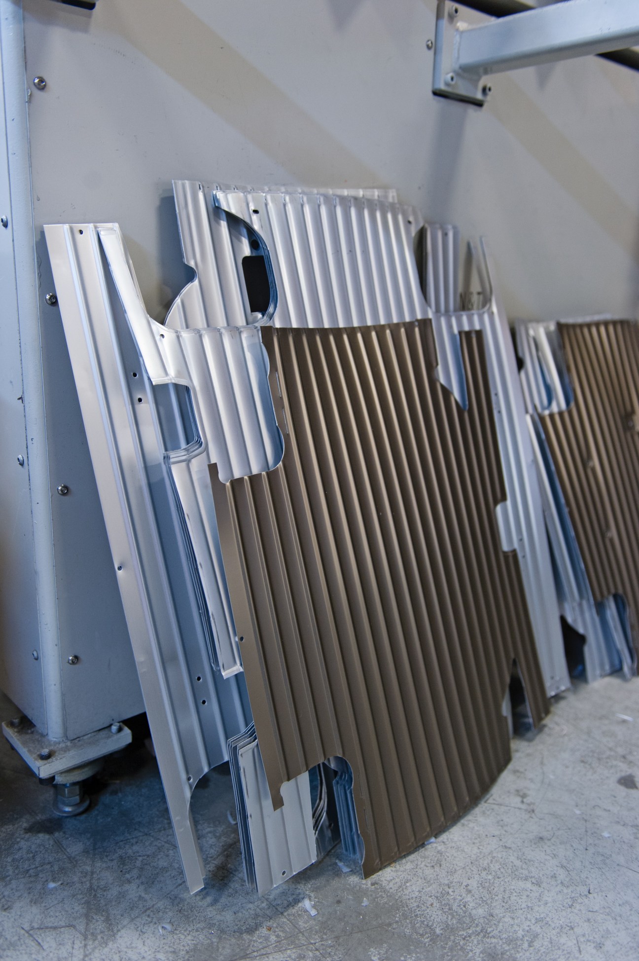 Stacked grooved metal panels in white and bronze aluminium alloy used for Rimowa suitcase production.