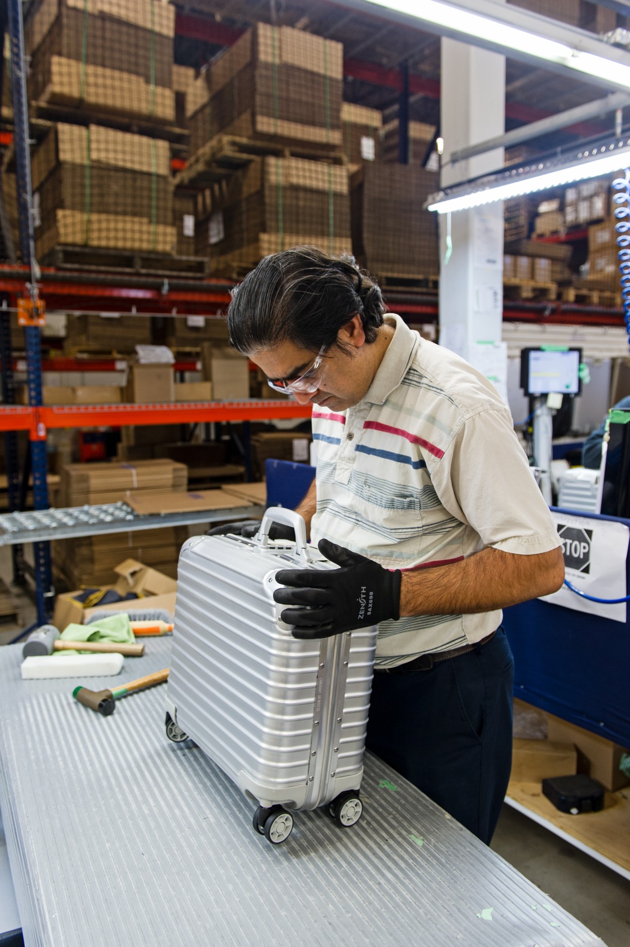 Worker assembling a silver Rimowa suitcase at the Cambridge manufacturing plant.