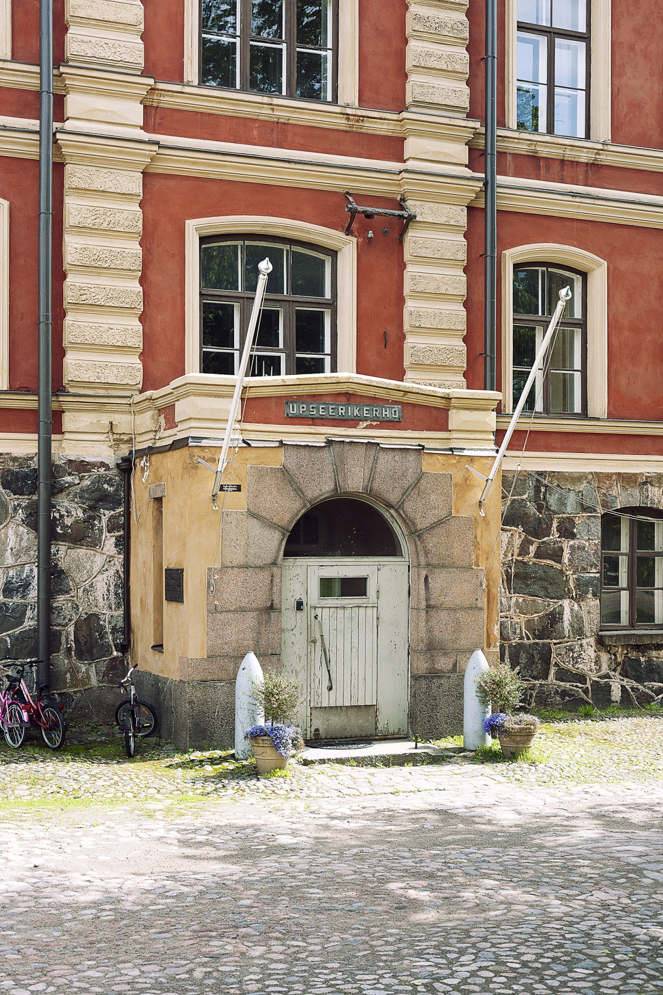 Red and cream-colored historic building with stone foundation and arched doorway labeled 'Upseerikerho' (officers' club).