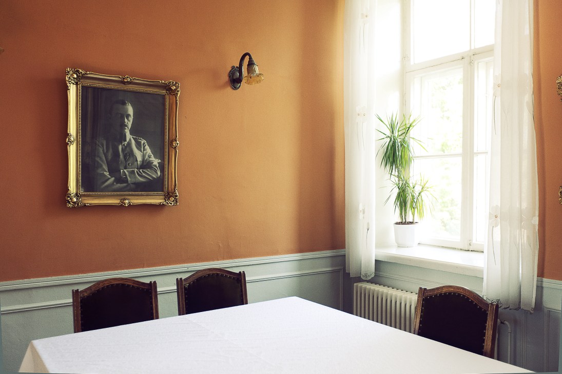Portrait of Carl Gustaf Mannerheim in ornate gold frame hanging on terracotta wall in officers' club.