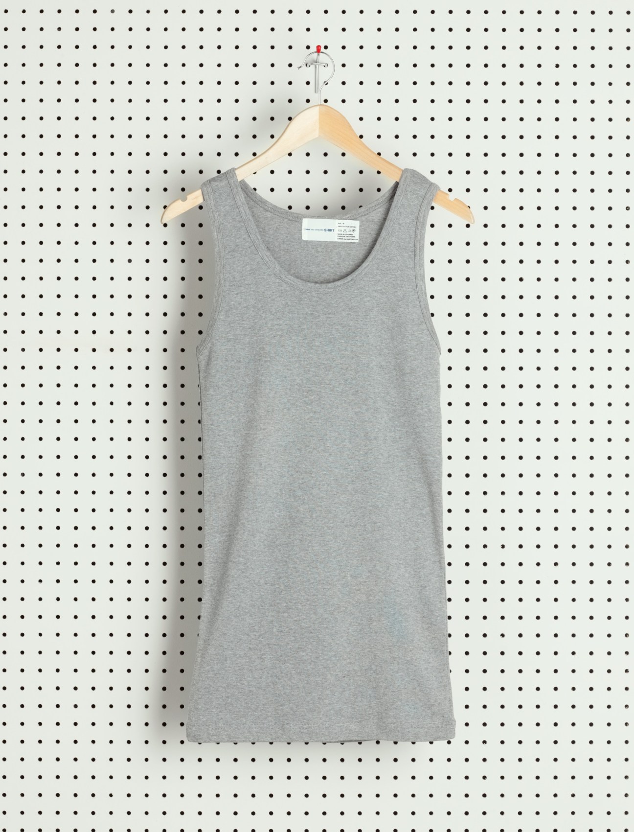Gray sleeveless tank top on wooden hanger against pegboard background.