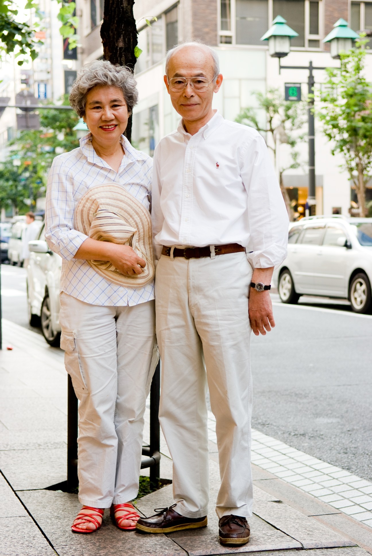 Tai Yamaguchi, 65, and her husband Hiroshi Yamaguchi, 67, pose on a Tokyo street wearing casual summer clothing.
