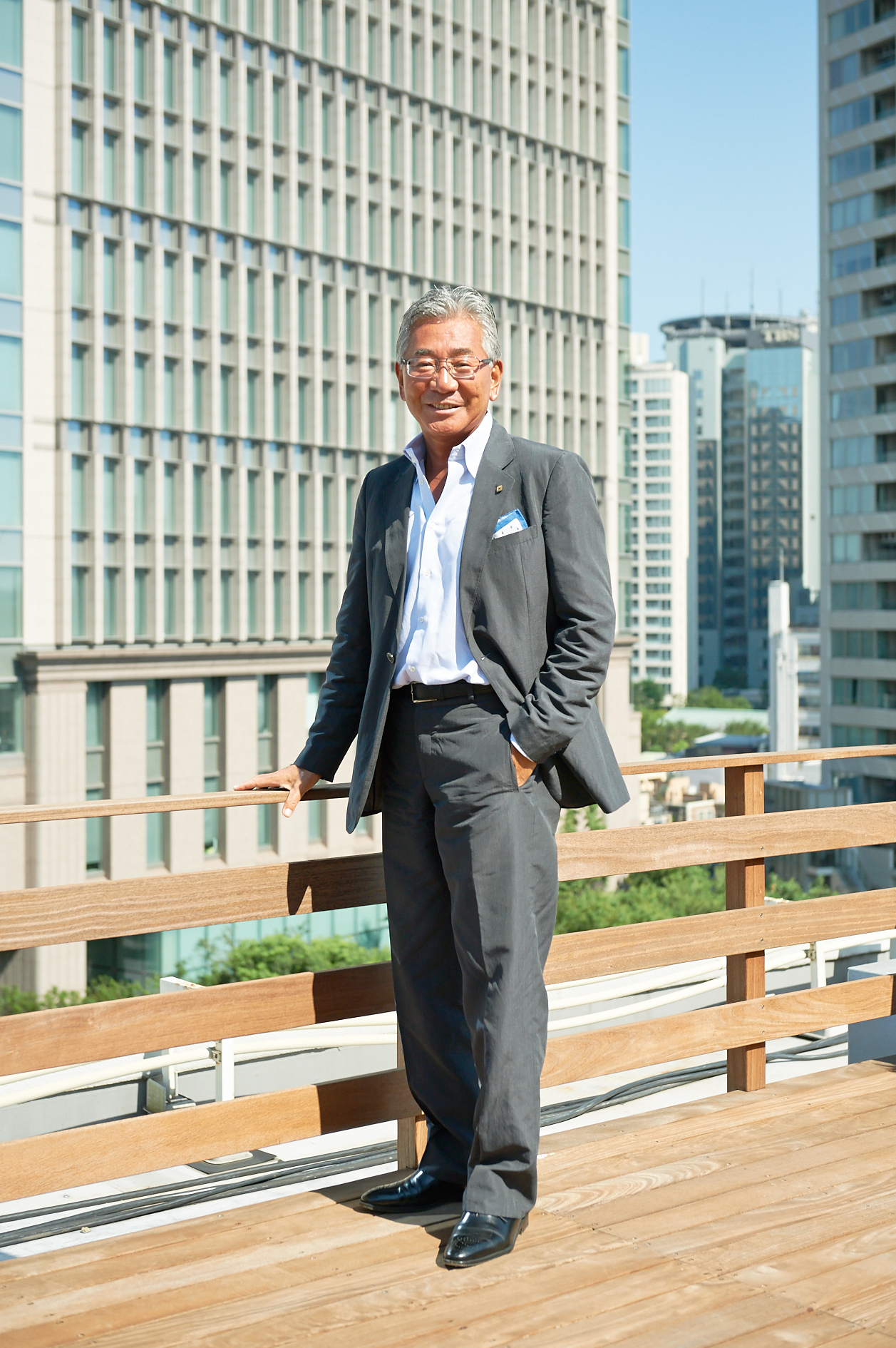 Hidetaka Yoshikawa, chief of Takara Belmont, stands on a rooftop terrace overlooking Osaka's skyline.