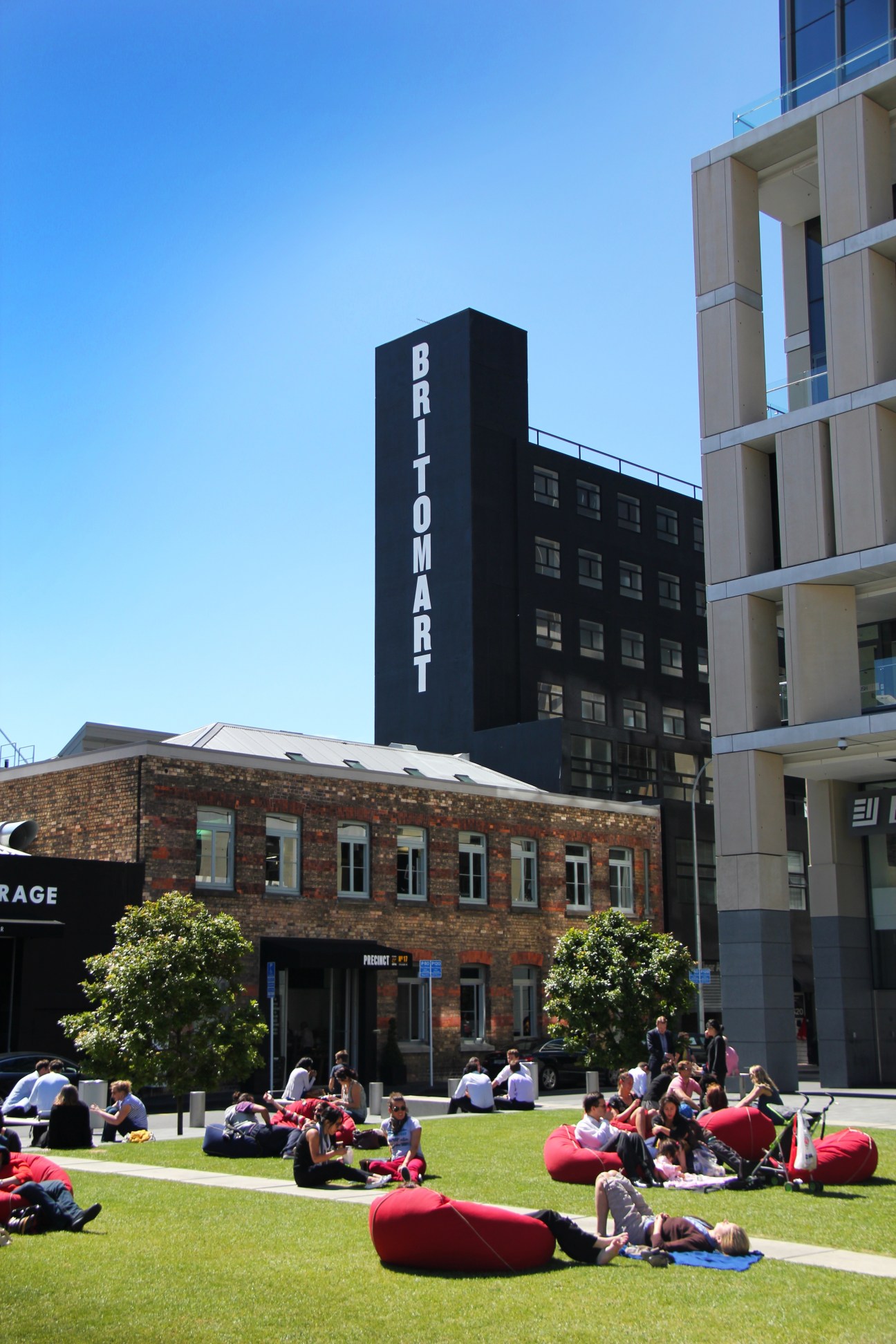 Britomart precinct in Auckland with pedestrians relaxing on red bean bags in a shared public space.