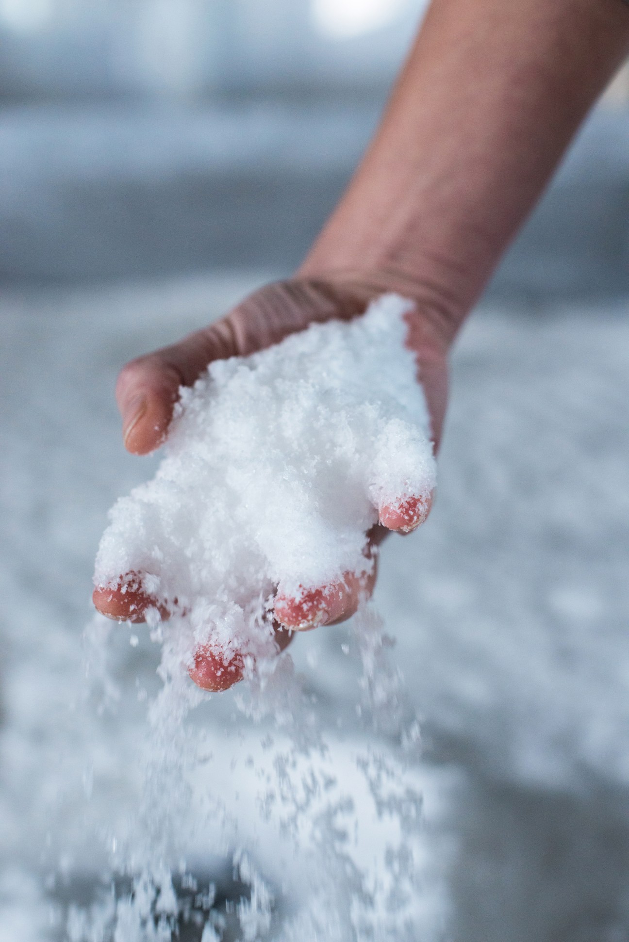 Hand holding bright-white sea salt crystals with water streaming down.