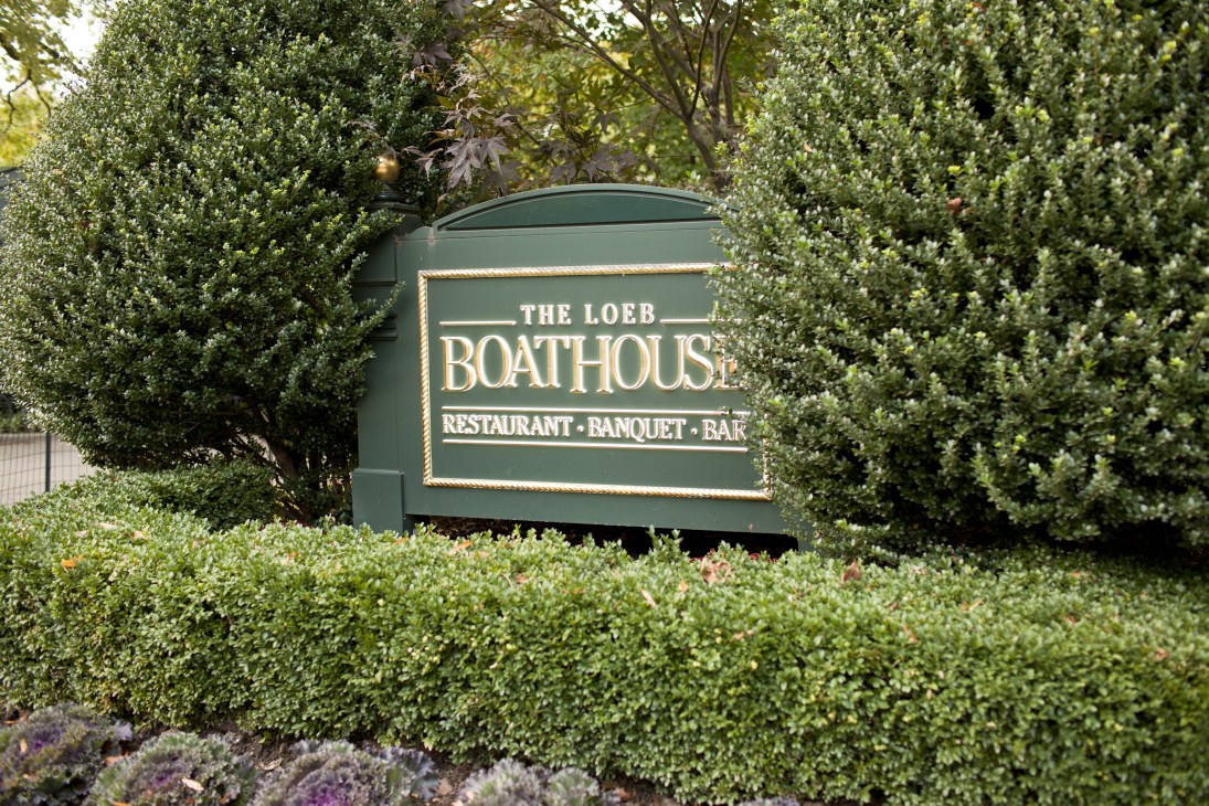 The Loeb Boathouse sign surrounded by green hedges and foliage in Central Park.