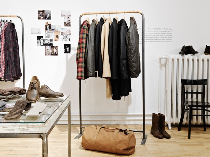 Interior of Très Bien shop in Malmö displaying clothing on metal racks and footwear on display tables.