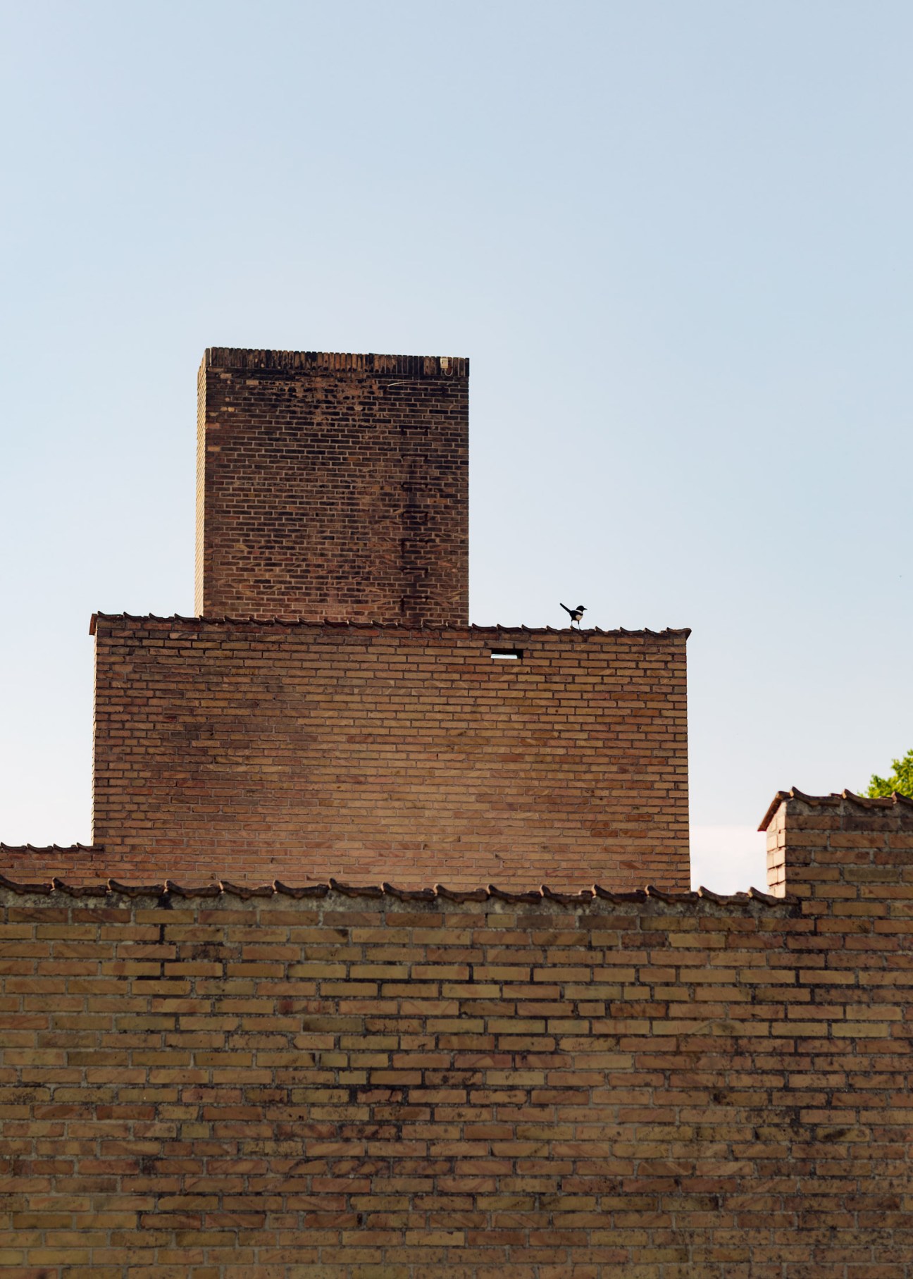 Brick chimneys and stepped walls of a Fredensborg House exterior against a clear sky.