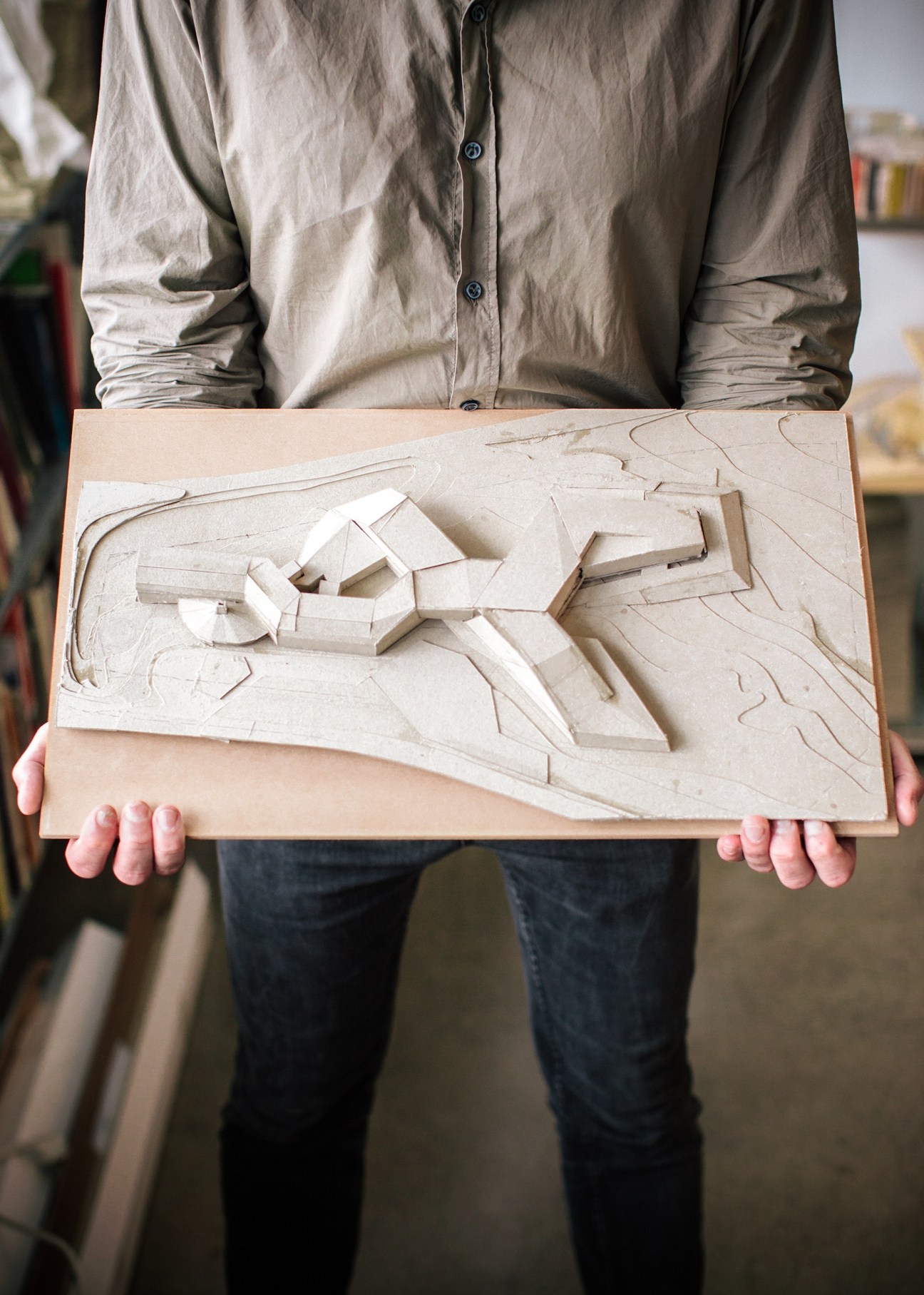 Person holding a wooden architectural model of JVA's tent-like science centre design for Svalbard.