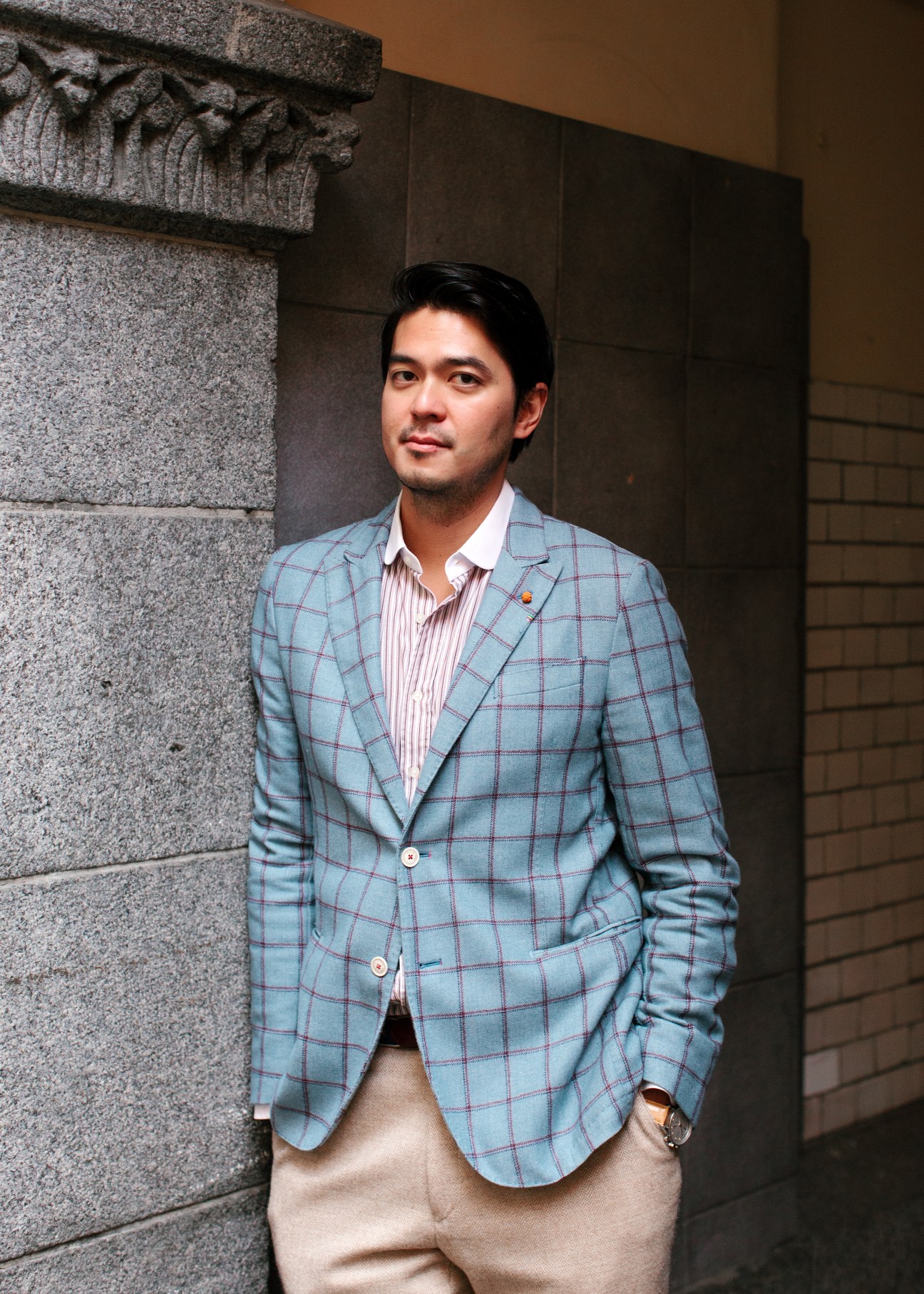 Tidal CEO Andy Chen wearing a blue plaid blazer stands against a stone wall at the company's Oslo office.