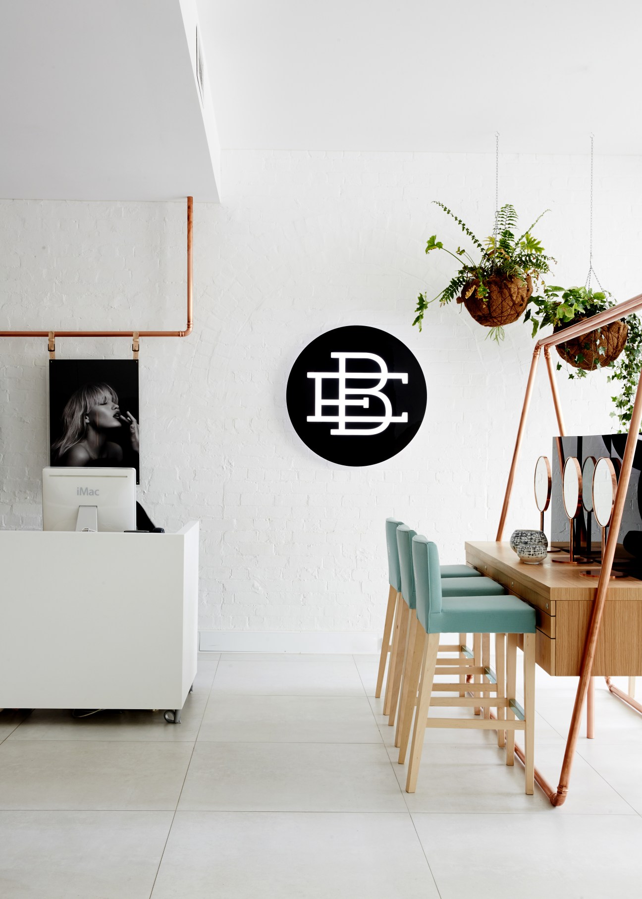 Modern interior space with wooden bar seating, hanging plants, and BVD logo on white brick wall.