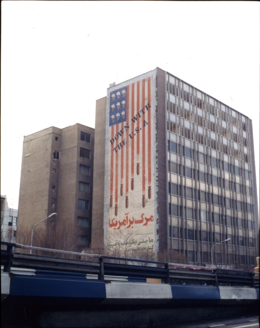 Building facade with anti-American mural featuring American flag with skulls and Persian text from early Islamic Revolution era