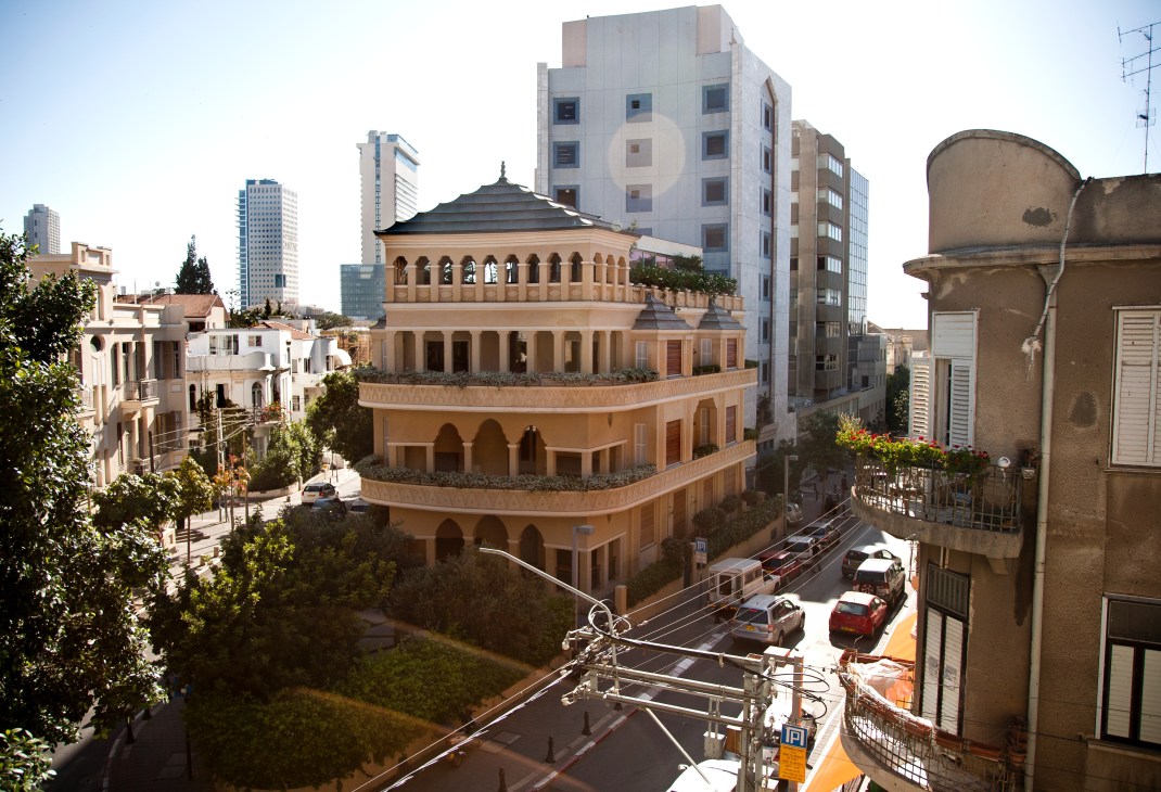 Aerial view of Montefiore's pagoda-house with arched colonnades surrounded by modern high-rises and historic buildings in Neve Tzedek, Tel Aviv.