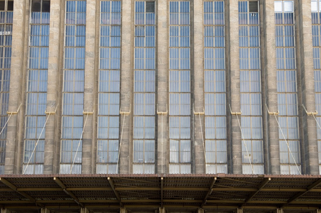 Tall narrow windows with blue glass panes on the concrete facade of Tempelhof airport building.