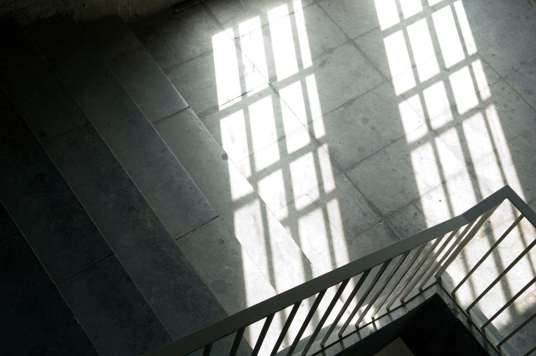 Sunlight streaming through large windows casts geometric shadow patterns on concrete walls inside Tempelhof airport's interior.