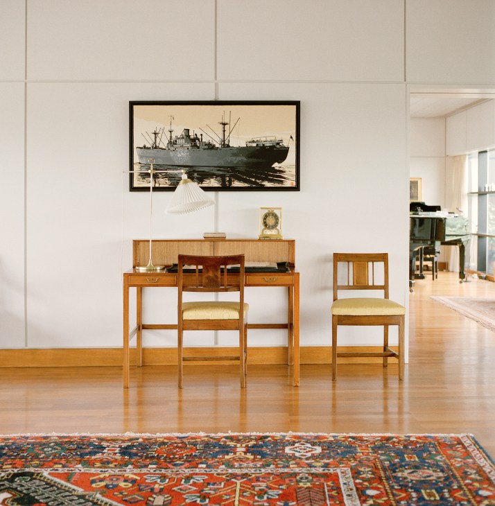 Wooden escritoire desk with chair beneath framed ship photograph, displaying wartime letters in Danish embassy reception room.