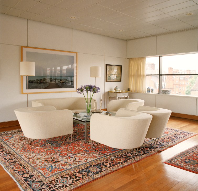 Modern living room with cream curved chairs, oriental rugs, and framed artwork in the Danish embassy residence.
