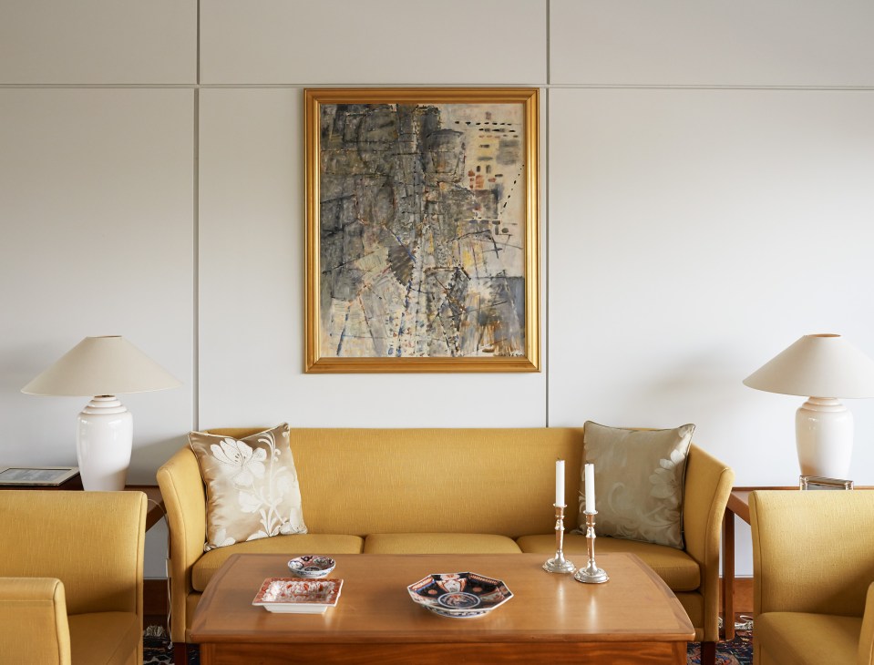 Gold sofa with decorative pillows and classic wooden coffee table in modern reception room.