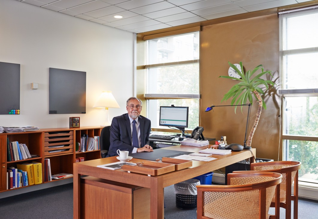 Danish ambassador Claus Grube sits at his wooden desk in a modernist office with mid-century furniture and large windows.
