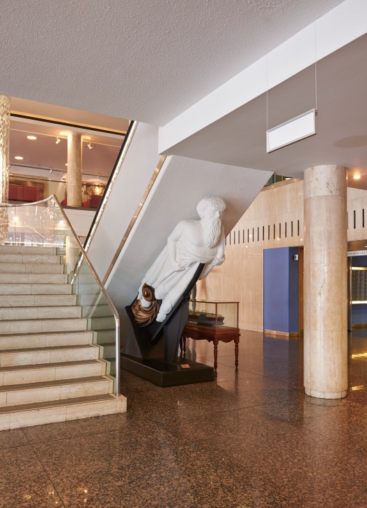 Ship's figurehead displayed inside IMO headquarters lobby beneath escalator.
