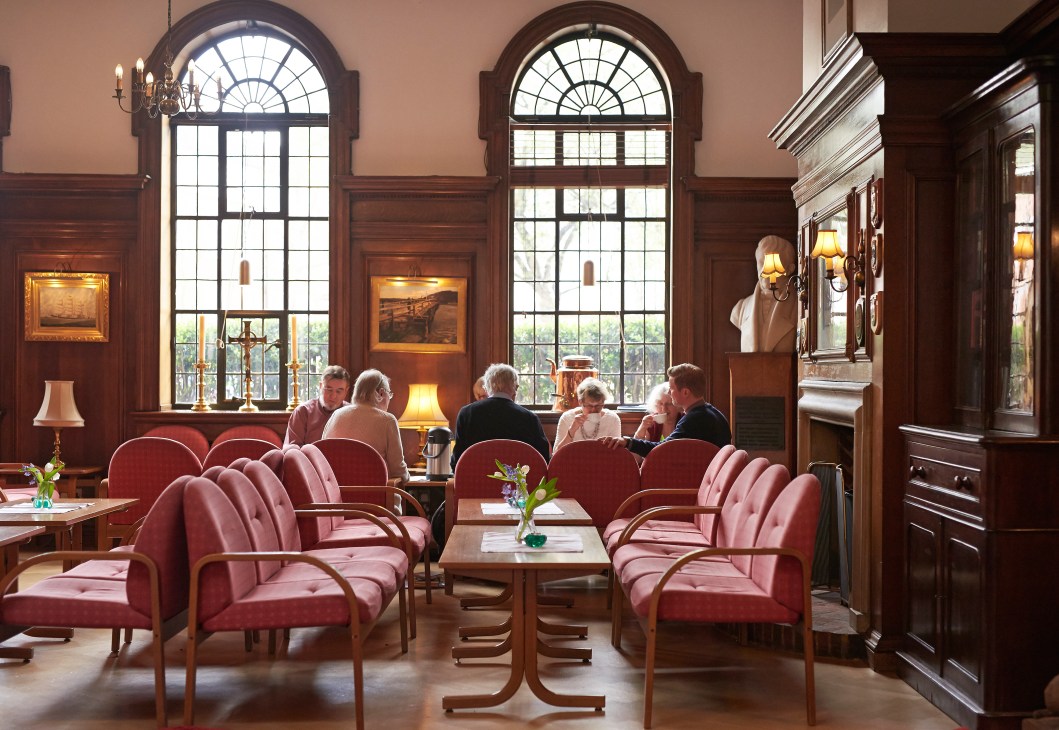 St Olav's reading room with red leather chairs, wood paneling, arched windows and maritime artwork.