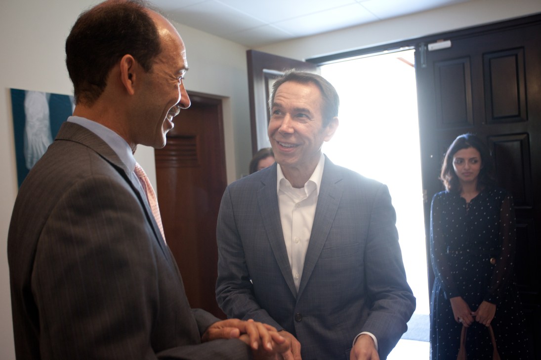 Jeff Koons and Ambassador Michael Corbin converse at an art exhibition opening.